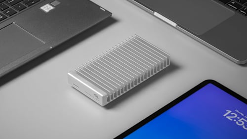 Express 1M2 Portable SSD surrounded by laptops and an iPad