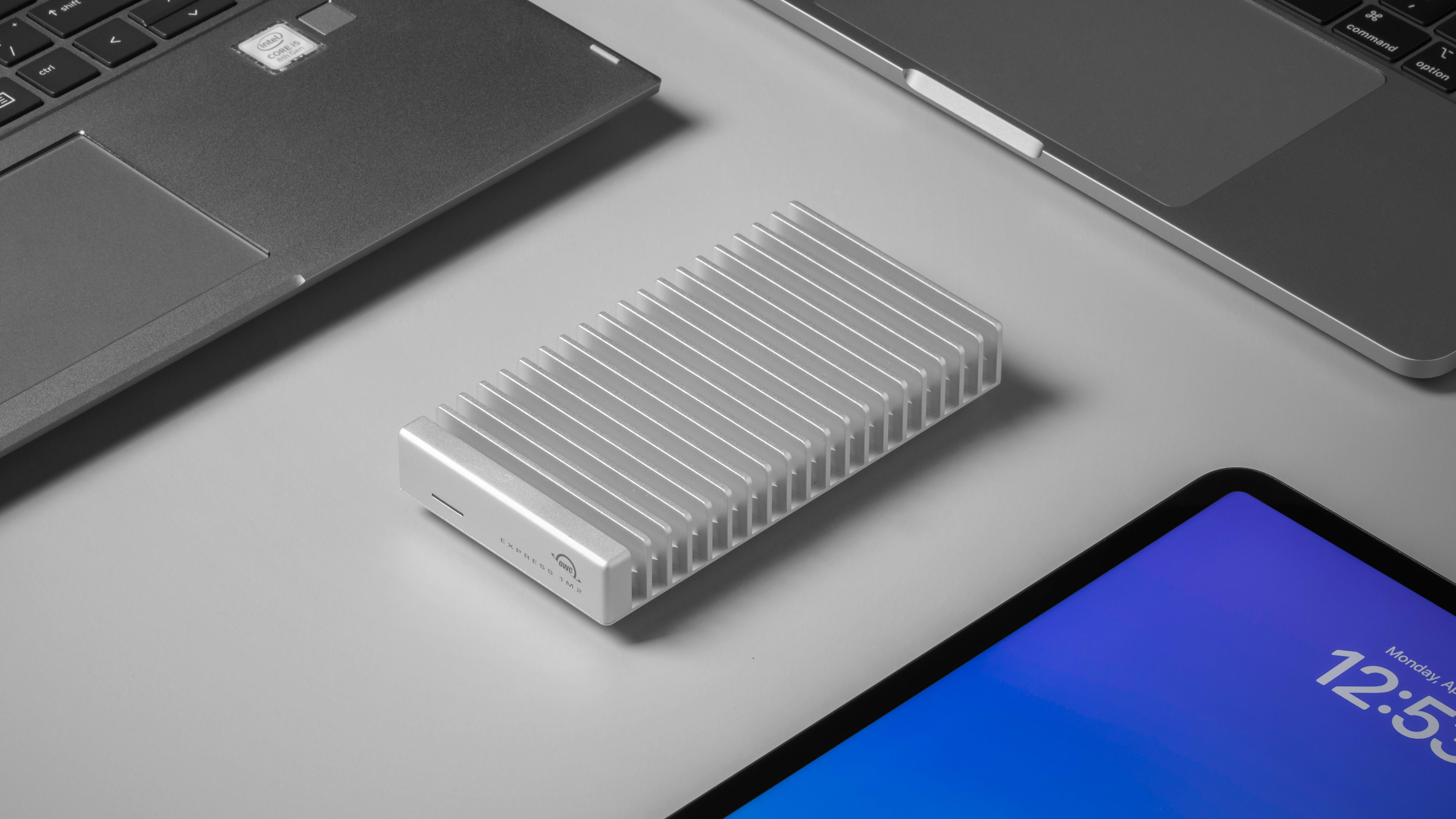 Express 1M2 Portable SSD surrounded by laptops and an iPad