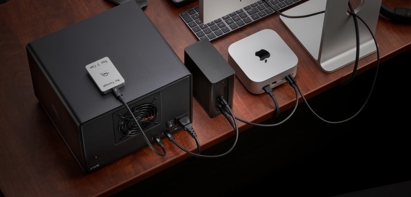 Rear, top-down view of OWC Express 4M2 Ultra on desktop connected to OWC Envoy, OWC ThunderBay 8, Mac mini, and display