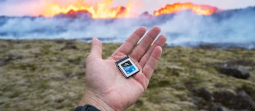 Hand holding OWC Atlas Pro CFexpress Memory Card with Volcano in background