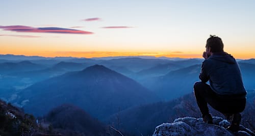 Man on mountain top at sunset