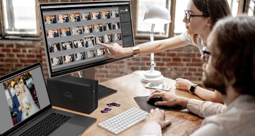Two photographers reviewing images with OWC Gemini Ultra on desktop