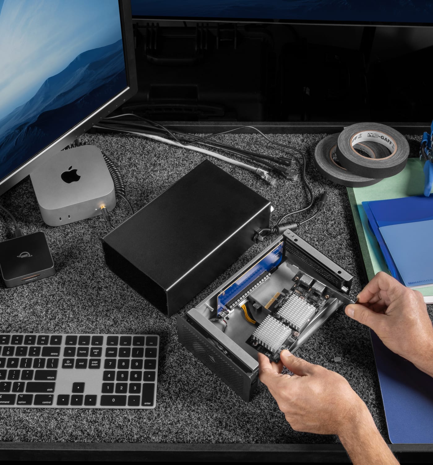 Closeup of a person's hands installing a PCIe card inside an OWC Mercury Helios 5S