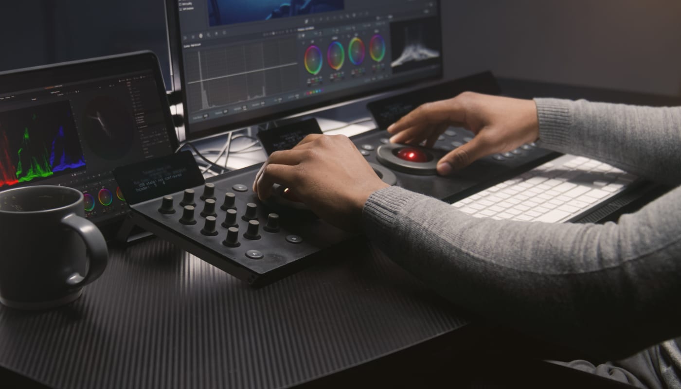 Professional colorist using control surface and DaVinci Resolve on a multi-display setup—ideal for high-bandwidth Thunderbolt 5 Dock workflows.