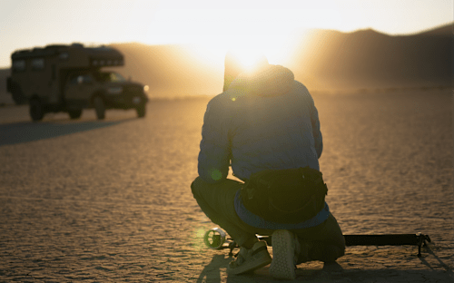 Individual setting up equipment with sunset in the background