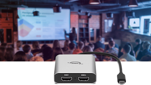 Closeup of am OWC USB-C Dual HDMI® 4K Display Adapter in front of an image of a meeting