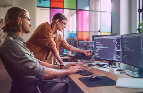 Two software developers working on multiple displays