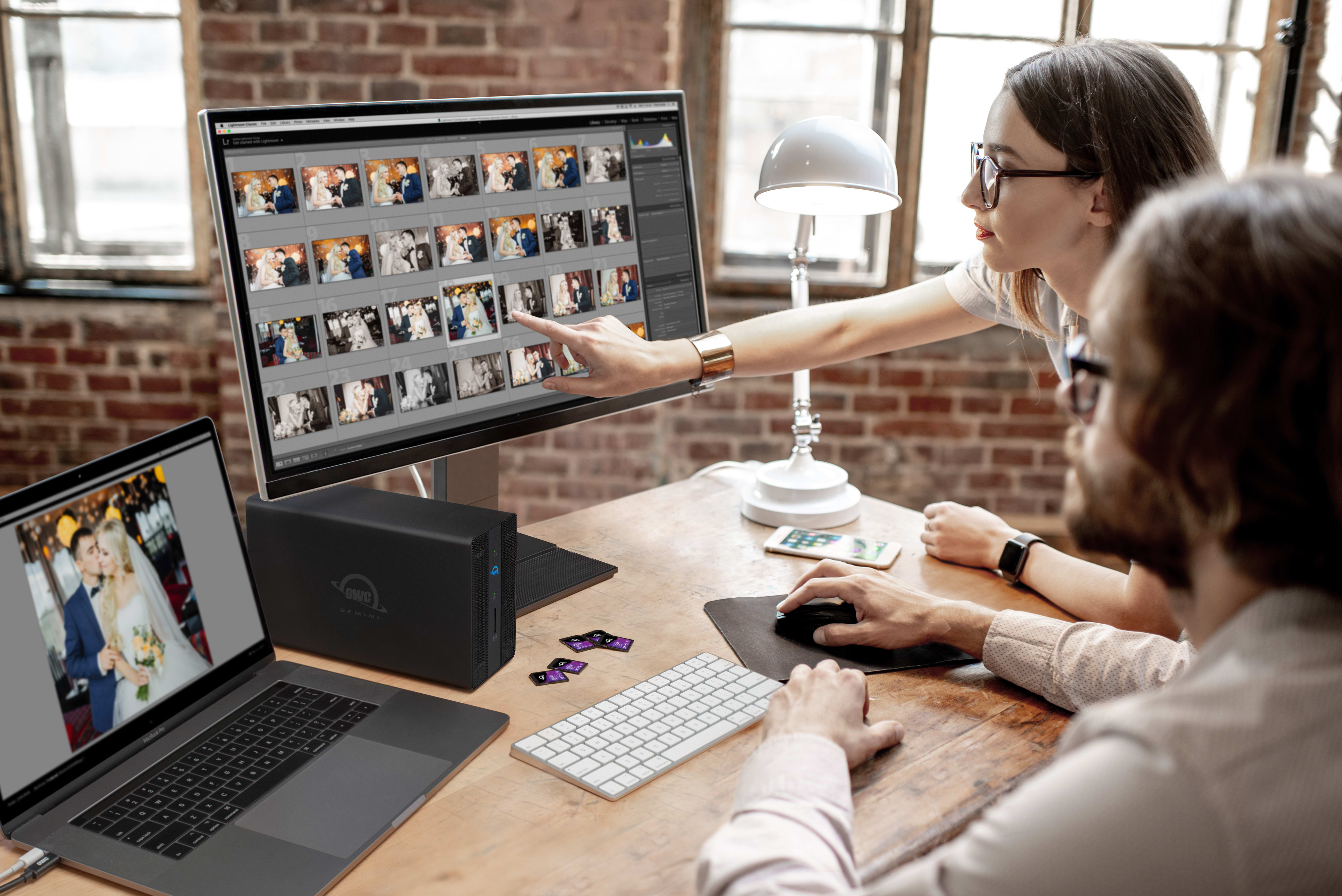 Photographers reviewing photos on desktop screen with OWC Gemini external storage
